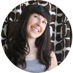 a woman with long dark hair smiling in front of a patterned wallpapered circle