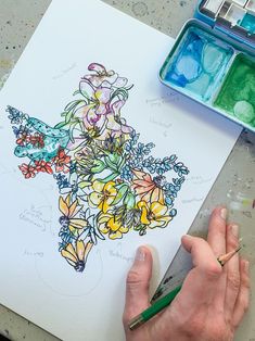 a person is drawing flowers on paper with colored pencils and watercoloring supplies