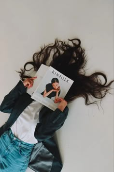 a woman laying on the floor with her hair flying in the air while reading a book