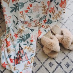 a pair of slippers sitting on top of a rug next to an open blanket