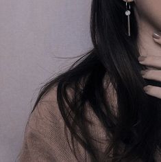 a woman with long black hair wearing earrings