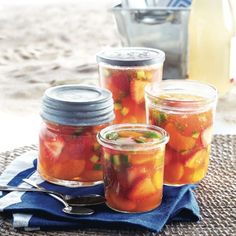 three jars filled with pickled fruit on top of a table next to a blue towel