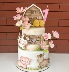 a three tiered cake decorated with farm animals and flowers