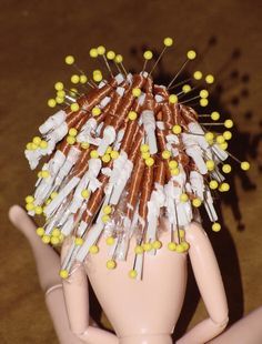 there is a doll with lots of needles on it's head and nails sticking out of her hair