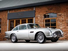 an old silver car parked in front of a brick building