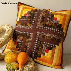 a decorative pillow sitting on top of a table next to pumpkins and gourds