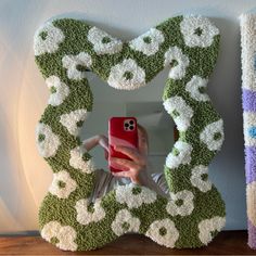 a woman taking a selfie with her cell phone in front of a flowered frame