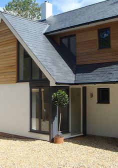 a large house with a black roof and white walls on the outside, surrounded by gravel