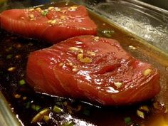 two raw fish fillets sit in a pan with sauce and seasonings on the side