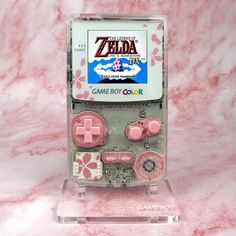 the nintendo gameboy is on display in a clear plastic case with pink and white buttons