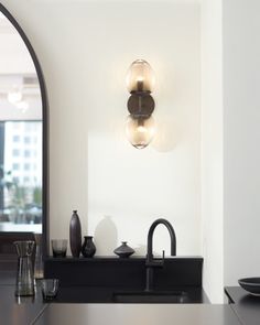 a kitchen with black counter tops and lights on the wall above it's sink