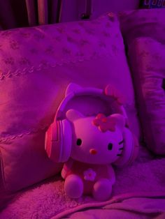 a hello kitty stuffed animal sitting on top of a bed next to pillows and headphones