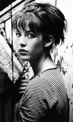 black and white photograph of a woman with short hair wearing a striped shirt looking at the camera