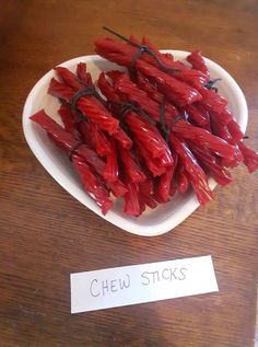 some red chili sticks are on a white plate next to a sign that says chew sticks