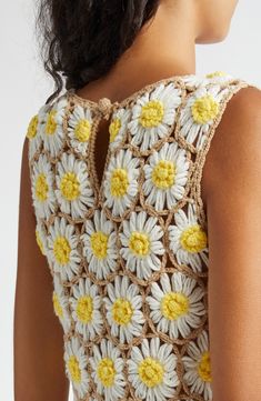 a woman is wearing a crocheted dress with yellow and white flowers on it