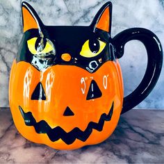 a ceramic mug with a cat's face painted on the side and eyes glowing