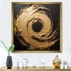 an abstract painting in gold and black on a white wall above a table with vases