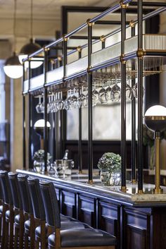 the bar is lined with wine glasses and vases on it's sides, along with black leather chairs