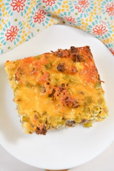 a white plate topped with a piece of food on top of a flowered table cloth