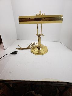 a desk lamp sitting on top of a white table next to a black and gold charger