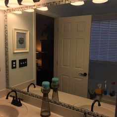 a bathroom with two sinks and a large mirror over the sink is lit by three lights