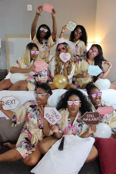 a group of women sitting on top of a bed holding up signs that say i love you