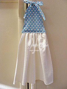 a blue and white dress hanging on the side of a refrigerator door with a bow at the top