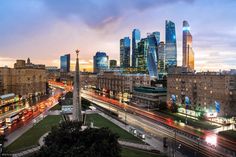 the city skyline is lit up at night with traffic moving by in the foreground