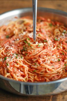 spaghetti being cooked in a pan with a fork