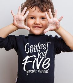 a young boy is holding his hands up in front of his face with the words coolest kid five years old