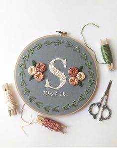 the embroidery kit is being used to make a monogrammed wall hanging with flowers