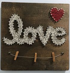 the word love is spelled with string and pegs on a wooden board that has clothes pins attached to it