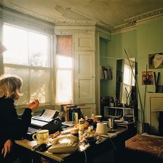 a woman sitting at a desk in front of a window with papers on the table