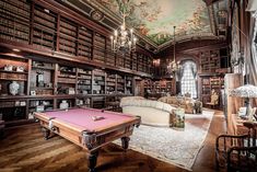 a pool table in the middle of a room with many bookshelves and couches