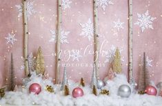 a pink and gold christmas backdrop with snowflakes, trees, ornaments and balls