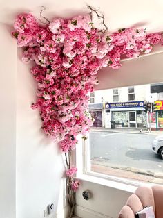 pink flowers are growing up the side of a window