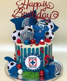 a birthday cake decorated with soccer balls and other sports related items is displayed on a plate