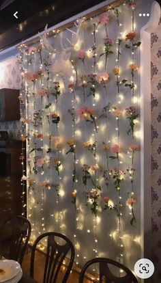 the flowers are hanging on the wall behind the chairs in the dining room, with fairy lights strung all over it