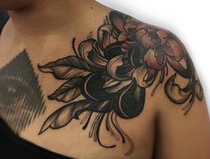 a woman's shoulder with flowers and leaves tattoo on her left side breast area