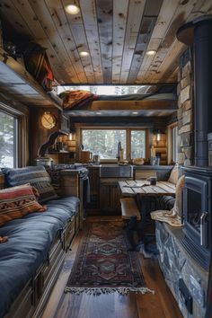 the interior of a small cabin with wood stove and couches in front of it