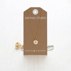 This necklace features a luminous 12mm Mother of Pearl hexagon as a honeycomb with a tiny bee. It hangs on an 18" vintage style beaded chain. The chain is 14k gold plated brass and coated to resist tarnish and create a hypoallergenic surface. Expertly crafted to last, this necklace showcases a radiant 12mm Mother of Pearl hexagon in the shape of a honeycomb with a delicate bee. The 18" chain boasts a vintage look and beaded design, constructed from 14k gold plated brass for a lustrous finish and Gold Hexagon Faceted Necklace, Minimalist Gold Hexagon Necklace, Hexagon Faceted Necklace For Gift, Hexagon Faceted Necklace For Gifts, Faceted Hexagon Necklace For Gift, Faceted Hexagon Necklace For Gifts, Sonoma California, Bee Necklace, Studio Logo