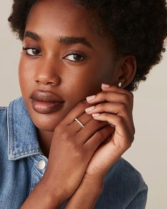 a close up of a person with a ring on her finger and wearing a denim shirt