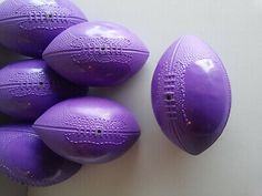 five purple plastic footballs sitting next to each other on a white surface with holes in the middle