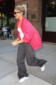 a woman walking down the sidewalk with her hand in her pocket