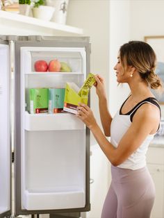 a woman opening the refrigerator door and looking at her product in it's display