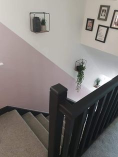 the stairs are painted pink and white with black railings on each side, along with pictures above them