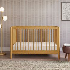 a baby's room with a crib, lamp and rug on the floor