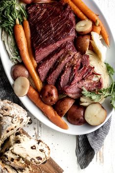 a white plate topped with meat, potatoes and carrots