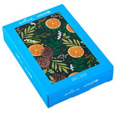 a blue box with oranges and pine cones on it's sides, sitting in front of a white background