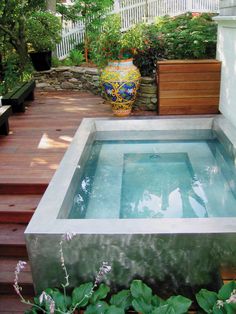 an outdoor hot tub surrounded by plants and flowers